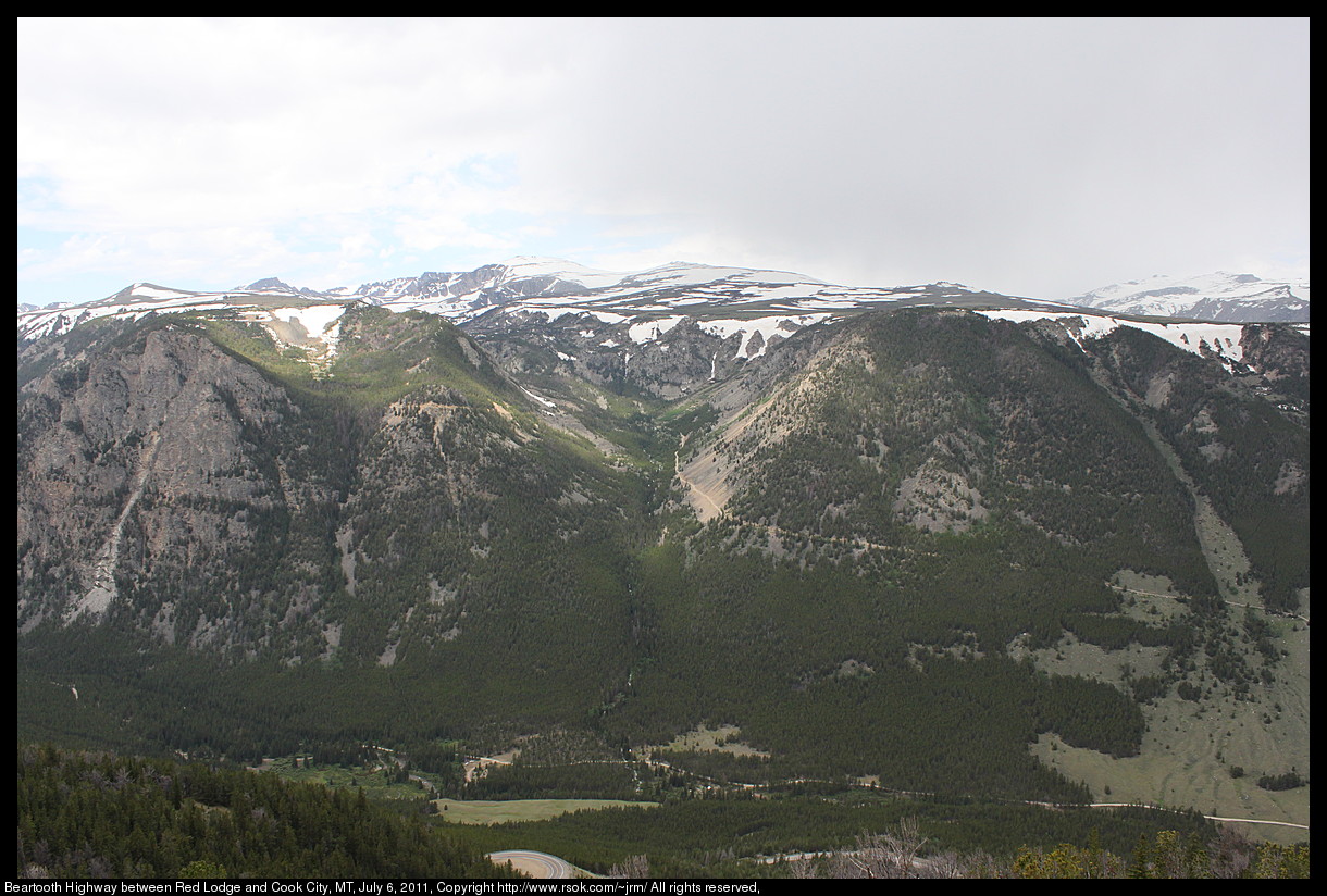 Snow capped mountains above a green valley.