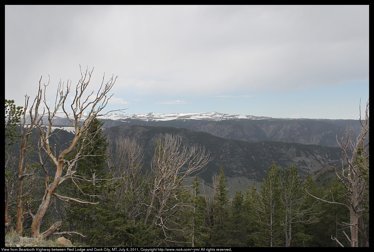 Snow capped mountains above a green valley.