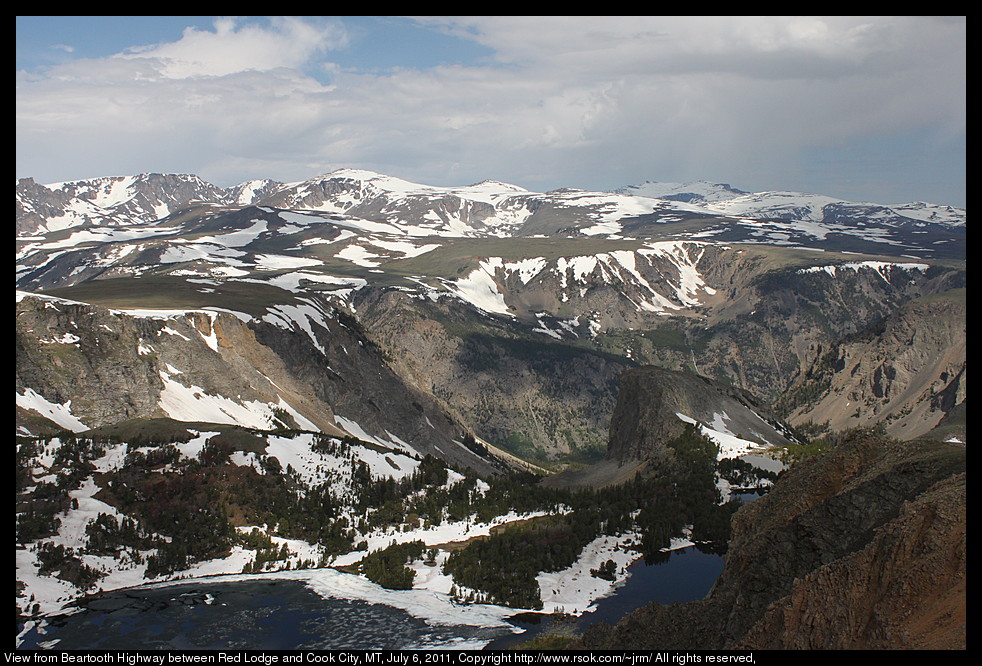 Snow capped mountains above a green valley.